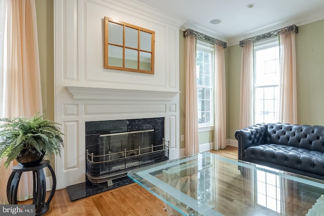 living area with a high end fireplace, light hardwood / wood-style floors, and ornamental molding