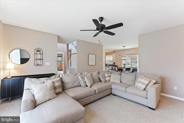 carpeted living room featuring ceiling fan with notable chandelier