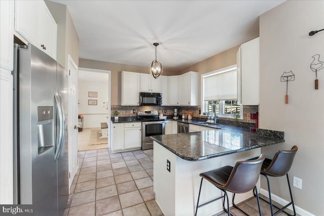 kitchen with white cabinets, decorative backsplash, appliances with stainless steel finishes, decorative light fixtures, and kitchen peninsula