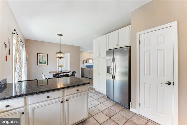 kitchen with dark stone counters, hanging light fixtures, stainless steel fridge with ice dispenser, light tile patterned floors, and white cabinetry