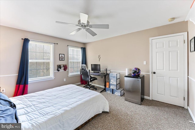 carpeted bedroom featuring ceiling fan and stainless steel refrigerator