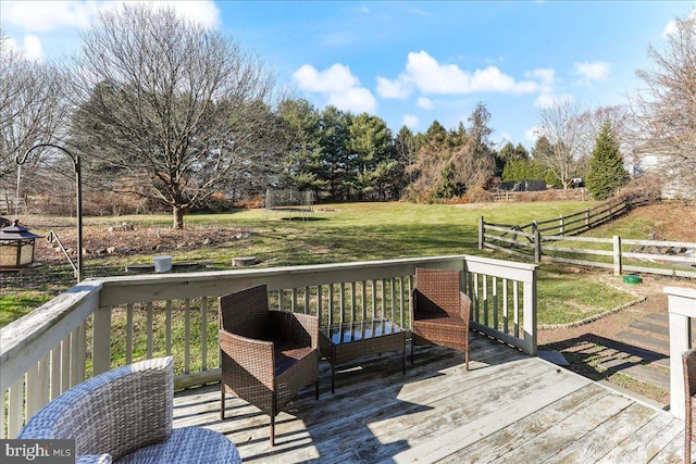 wooden terrace with a lawn and a trampoline