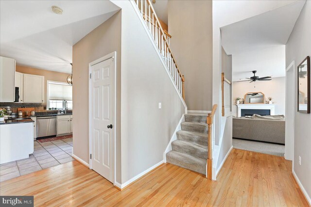 stairs with ceiling fan, hardwood / wood-style floors, and sink