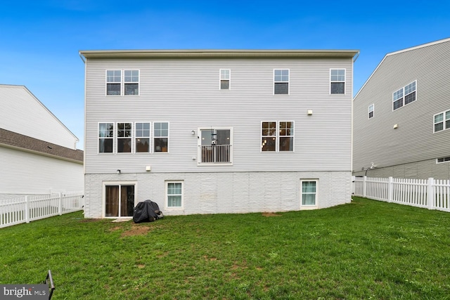 back of house with a fenced backyard, a lawn, and brick siding