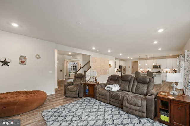 living area featuring baseboards, stairway, light wood-style flooring, and recessed lighting