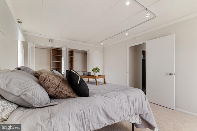 carpeted bedroom featuring crown molding and track lighting