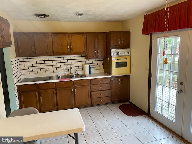 kitchen featuring light tile patterned floors, white oven, tasteful backsplash, and sink