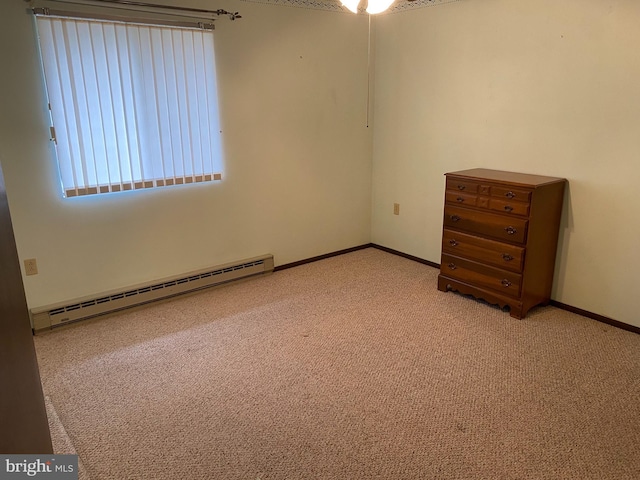 carpeted empty room featuring a baseboard heating unit