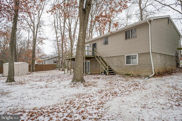 snow covered house with a deck and a storage shed