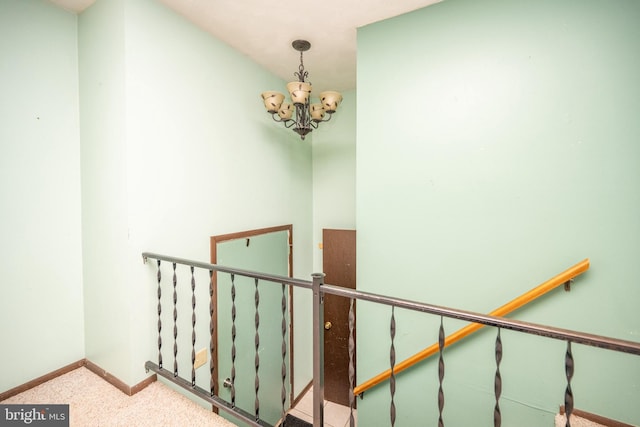 staircase with carpet floors and an inviting chandelier