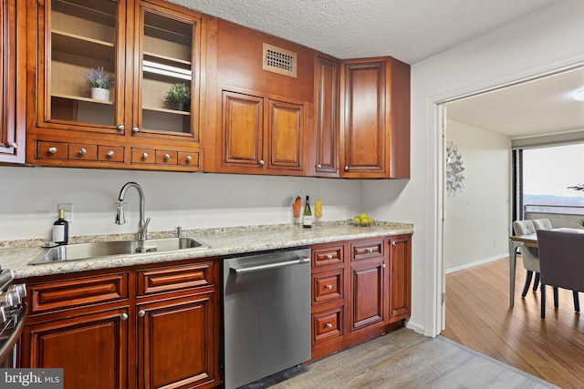 kitchen featuring light stone counters, a textured ceiling, sink, light hardwood / wood-style flooring, and dishwasher