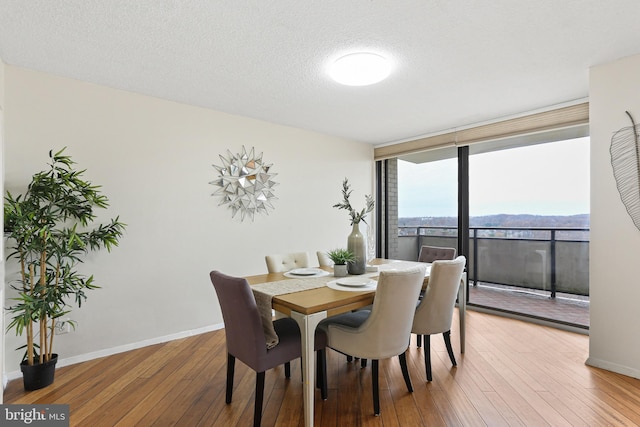 dining room with a textured ceiling, hardwood / wood-style flooring, and a wall of windows