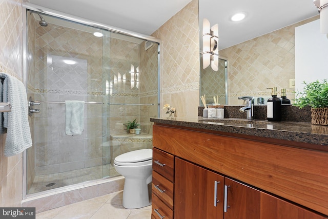 bathroom featuring tile patterned floors, vanity, a shower with door, tile walls, and toilet