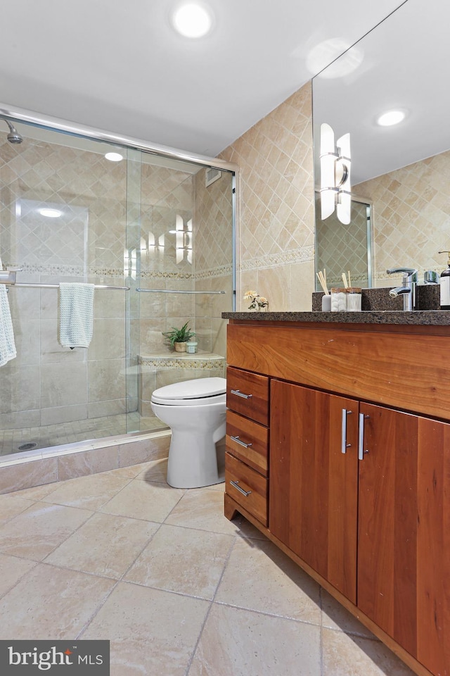 bathroom with vanity, toilet, tile walls, and walk in shower