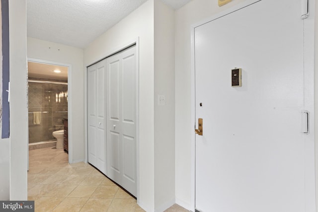 corridor with light tile patterned flooring and a textured ceiling