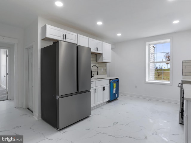 kitchen featuring white cabinetry, dishwasher, sink, tasteful backsplash, and stainless steel fridge