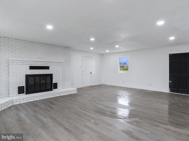 unfurnished living room with hardwood / wood-style floors and a brick fireplace