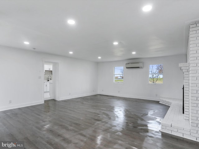 unfurnished living room featuring sink, dark wood-type flooring, and a wall mounted AC