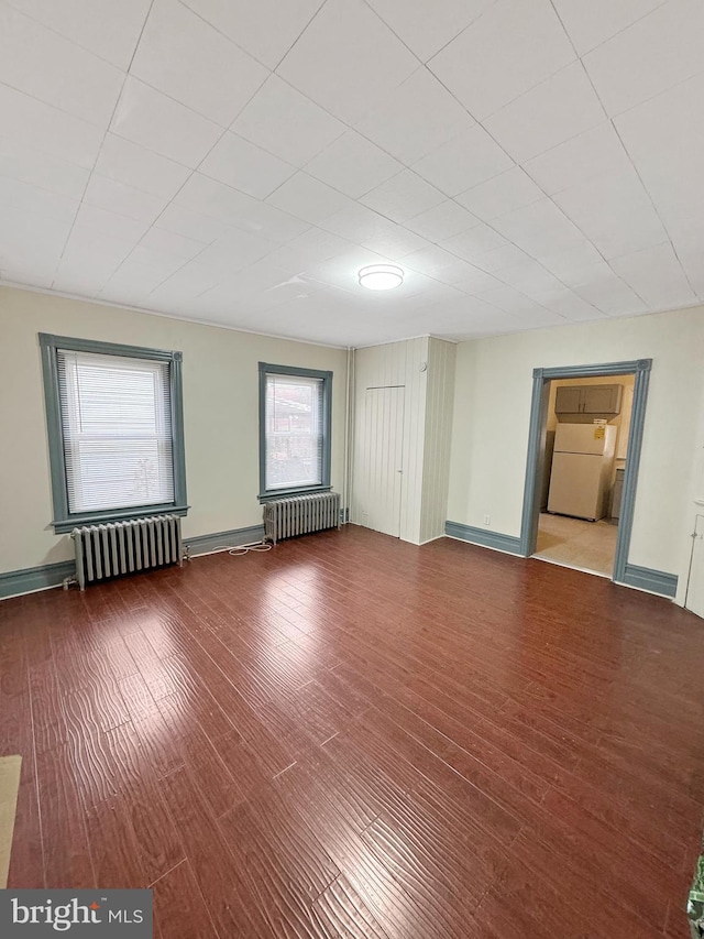 spare room featuring radiator heating unit and hardwood / wood-style floors