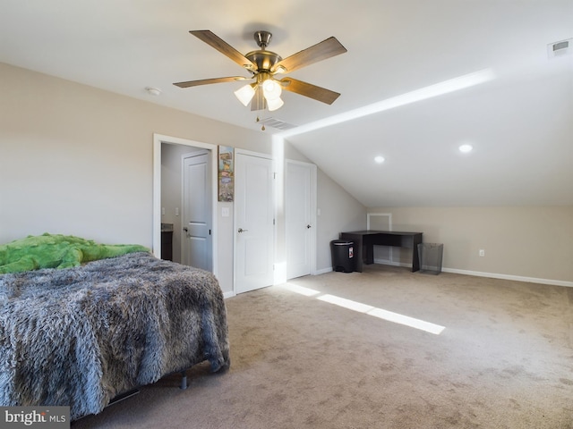 carpeted bedroom featuring multiple closets, ceiling fan, and vaulted ceiling