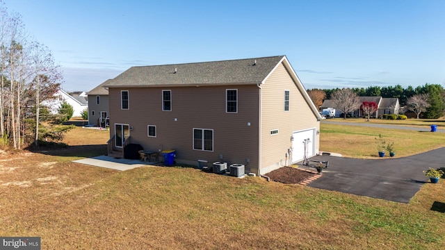 back of property featuring a lawn, a garage, and central air condition unit