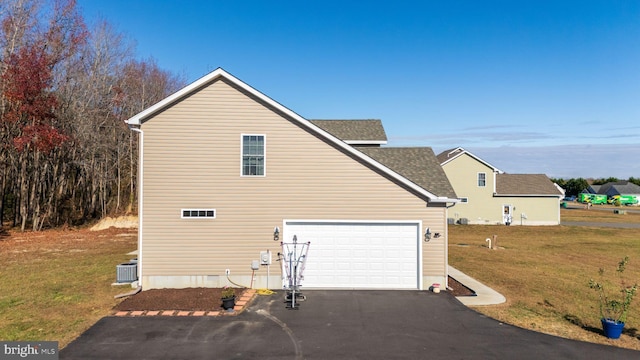 view of side of home featuring cooling unit, a garage, and a yard