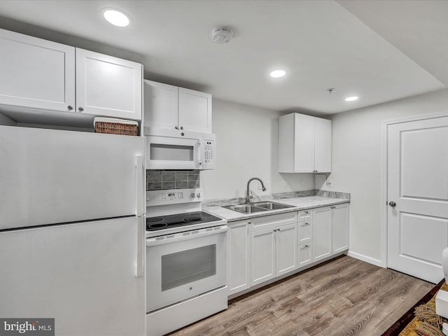 kitchen with decorative backsplash, white appliances, sink, light hardwood / wood-style floors, and white cabinetry