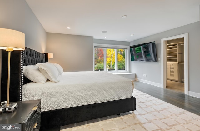 bedroom with a closet, a spacious closet, and hardwood / wood-style floors