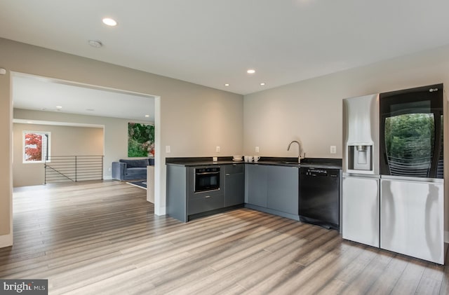 kitchen featuring sink, light hardwood / wood-style floors, and black appliances