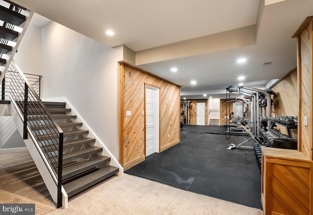 exercise area featuring carpet flooring and wood walls