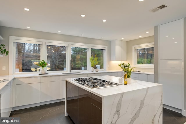 kitchen with plenty of natural light, a center island, white cabinetry, and sink