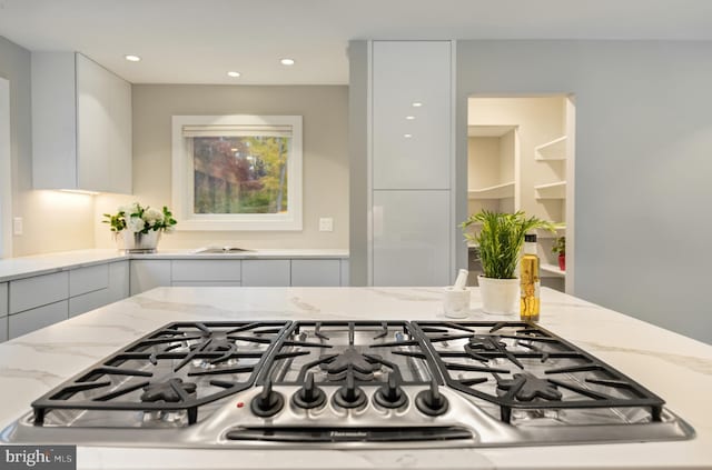 kitchen with light stone counters, white cabinets, and stainless steel gas cooktop