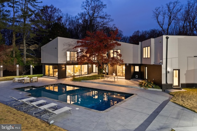 pool at dusk featuring a patio area