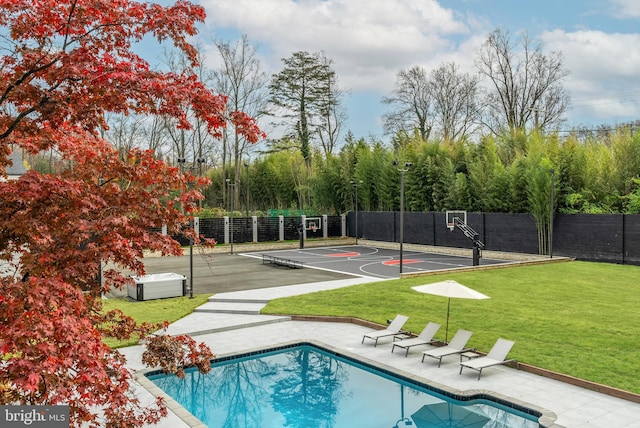 view of basketball court with a fenced in pool and a lawn