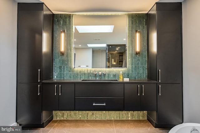 bathroom with tile patterned flooring, vanity, tasteful backsplash, and a skylight