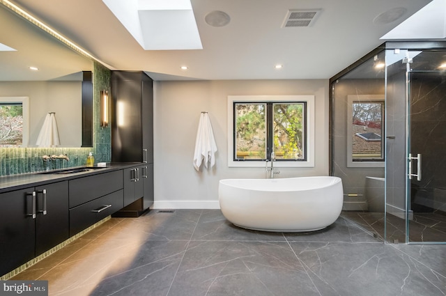 bathroom with shower with separate bathtub, vanity, a skylight, and tasteful backsplash