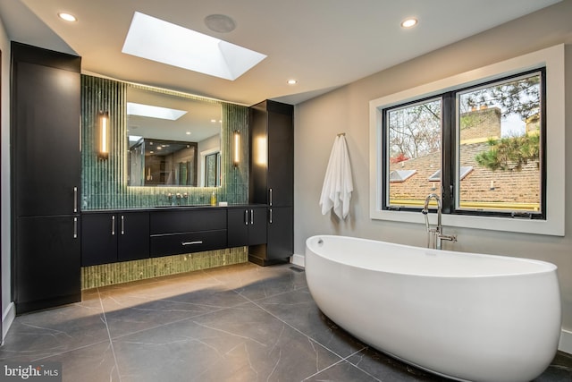 bathroom featuring a skylight, a washtub, and vanity