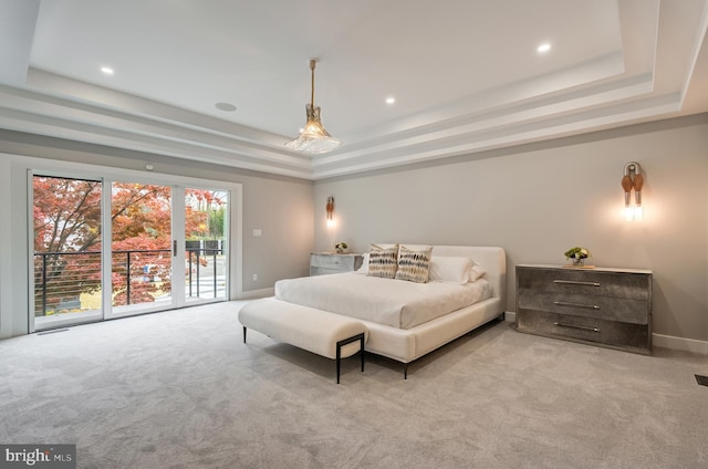 carpeted bedroom featuring french doors, access to outside, and a tray ceiling