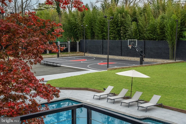 view of basketball court featuring a fenced in pool and a yard