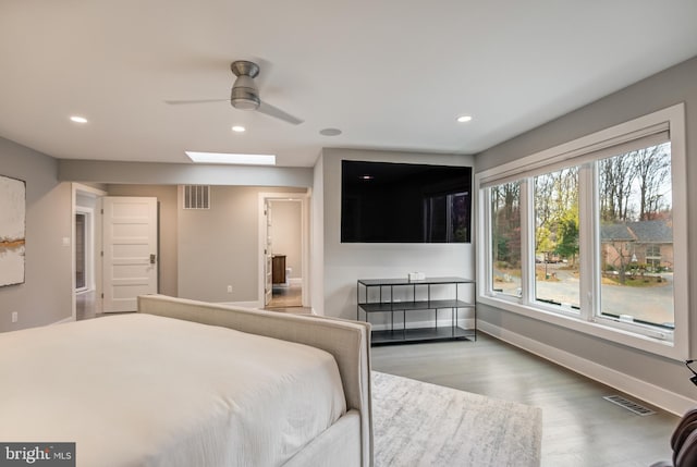 bedroom featuring hardwood / wood-style floors, ceiling fan, and a skylight