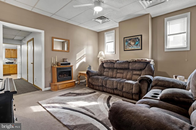 living room featuring a drop ceiling, ceiling fan, and light colored carpet