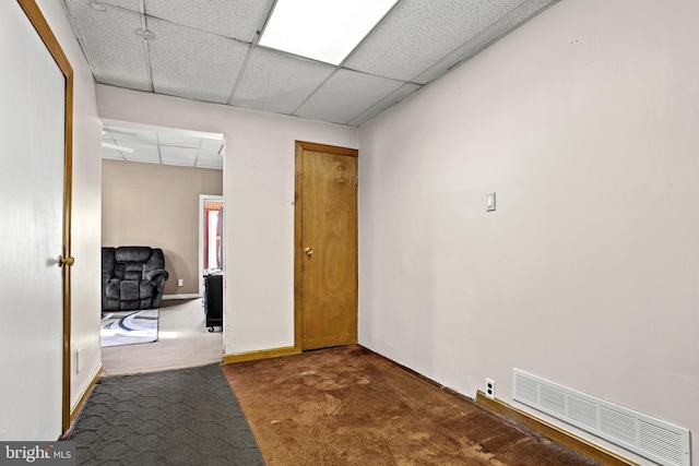 hall featuring a paneled ceiling and dark carpet