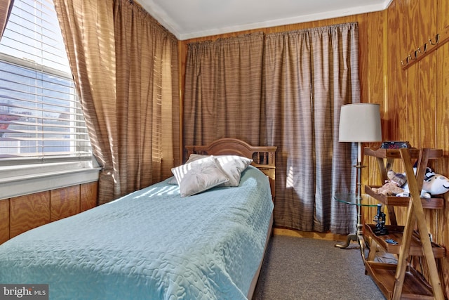 carpeted bedroom with ornamental molding and wooden walls