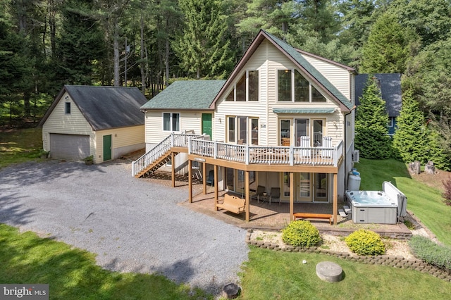 rear view of house with an outbuilding, a patio, a wooden deck, and a hot tub