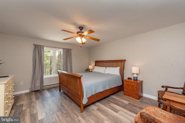 bedroom with baseboard heating, light hardwood / wood-style flooring, and ceiling fan