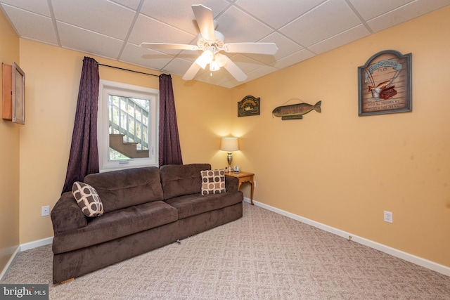 living room with ceiling fan, a drop ceiling, and carpet floors