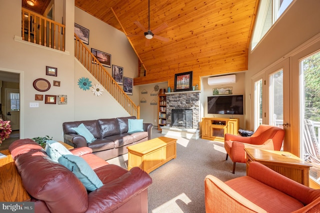 living room featuring a wall mounted air conditioner, carpet flooring, ceiling fan, high vaulted ceiling, and a stone fireplace