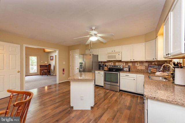 kitchen with light stone countertops, sink, dark hardwood / wood-style floors, white cabinets, and appliances with stainless steel finishes