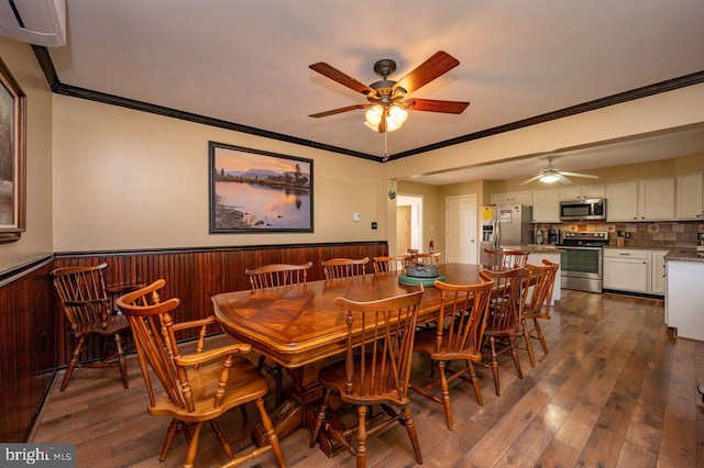 dining space featuring ceiling fan, dark hardwood / wood-style flooring, ornamental molding, and wooden walls