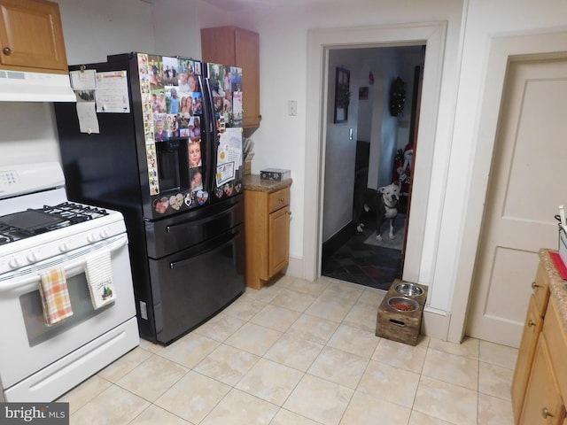 kitchen with black refrigerator, light tile patterned flooring, gas range gas stove, and exhaust hood